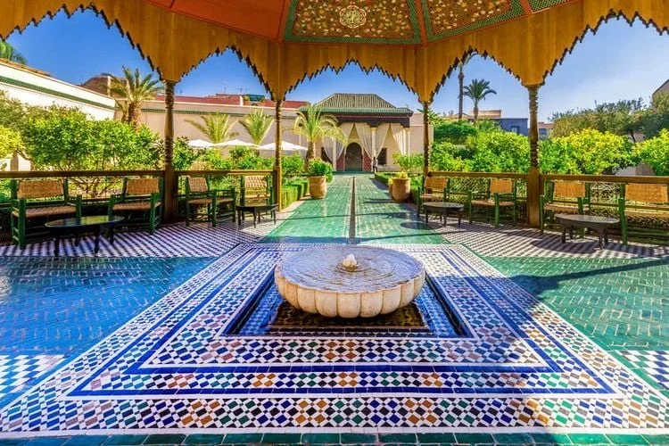 Marble fountain centered on intricate blue and green geometric floor tiles.