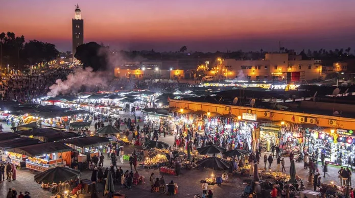 A panoramic view of Jemaa el-Fna Square in Marrakech under a bright blue sky.