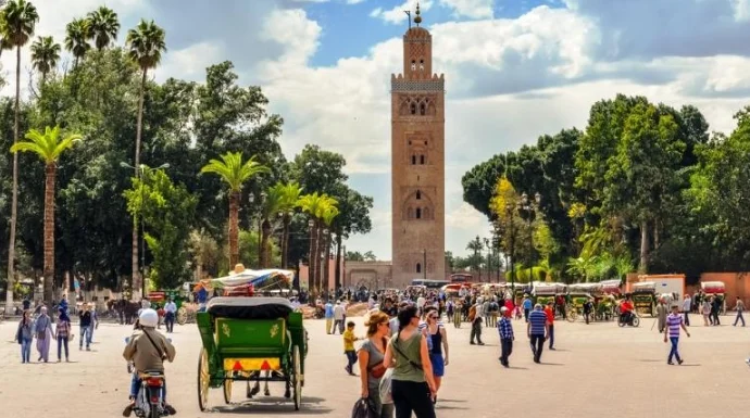 The tall stone minaret of the Koutoubia Mosque stands against a clear sky.