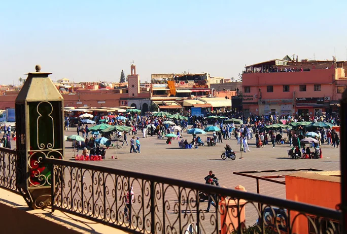 People sit at rooftop café tables overlooking the busy Jemaa el-Fna Square.