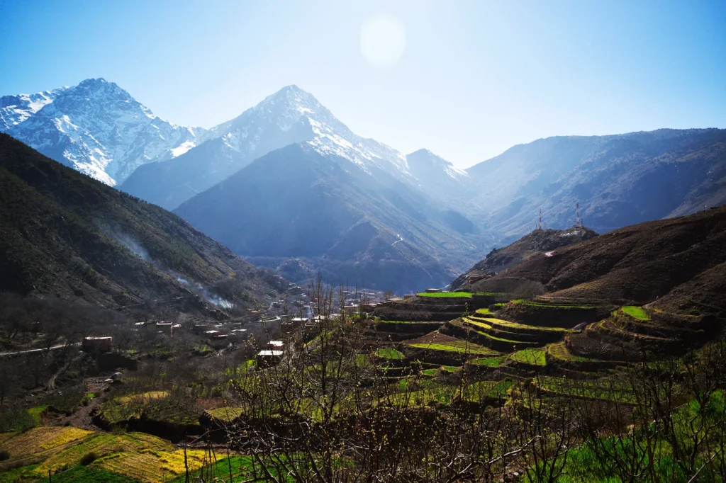 Snow-capped rugged mountain peaks towering over a deep, rocky green valley.