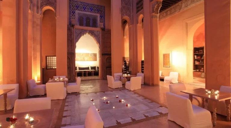 A candlelit riad courtyard with elegant arches and white lounge seating at night.