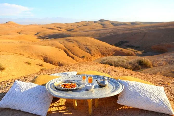 White luxury tents pitched across rolling desert hills under a pale sunset sky.