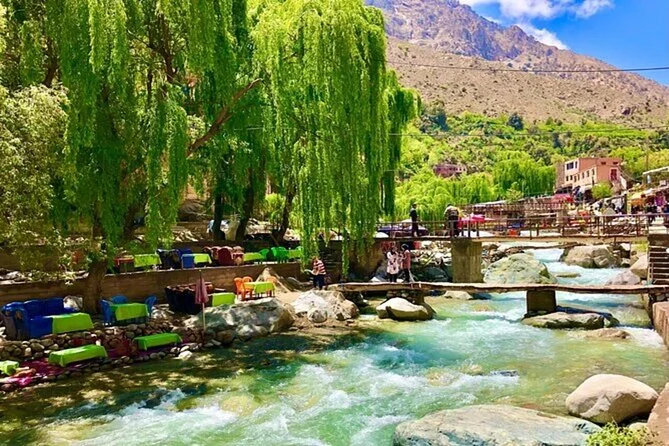 A rushing mountain river flanked by lush green trees and outdoor restaurant seating.
