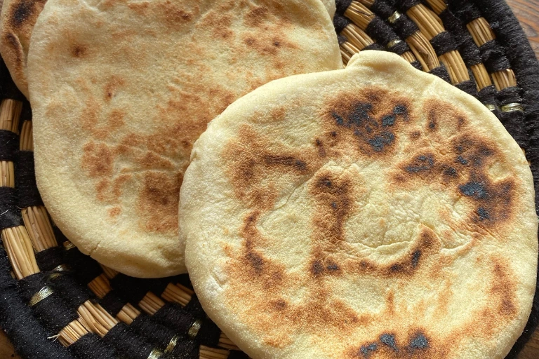 Two pieces of warm homemade flatbread served on a woven traditional basket.