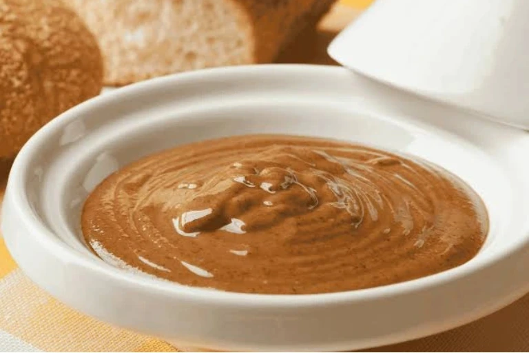 A bowl of rich and creamy Amlou served with fresh bread for a tasty breakfast.