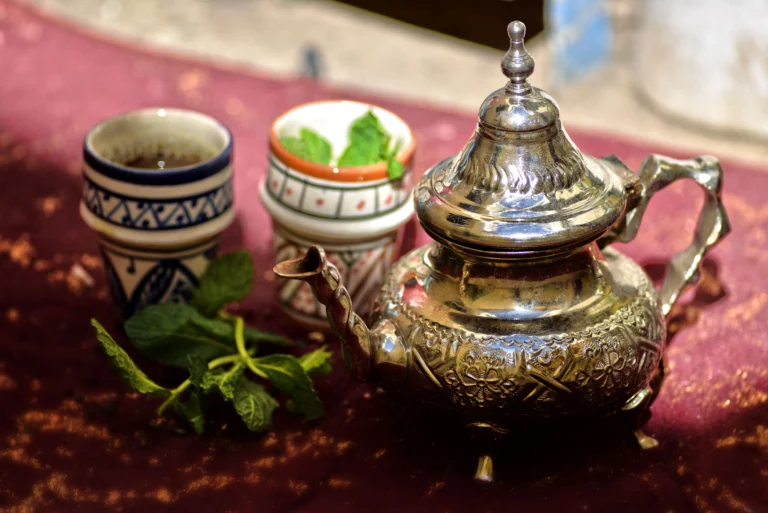 Moroccan mint tea served with a decorative silver teapot and colorful glasses.