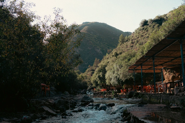 Outdoor seating at a peaceful café located next to a flowing mountain stream.
