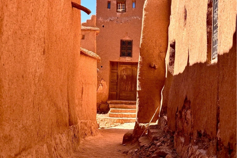 Soft sunlight illuminates a narrow, sandy passageway in the clay village.
