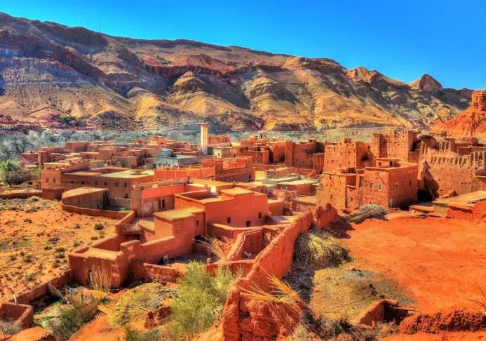 Traditional red clay desert village built at the foot of rugged rocky mountains