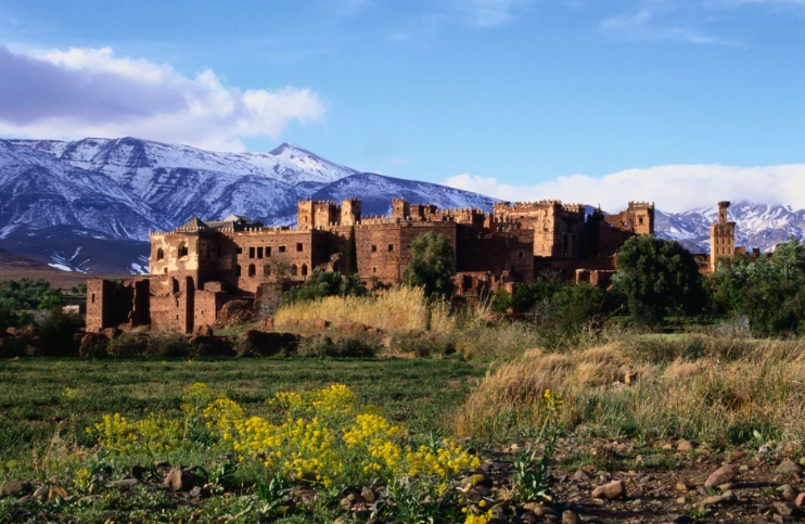 Historic Kasbah surrounded by snow-capped Atlas Mountains and fields