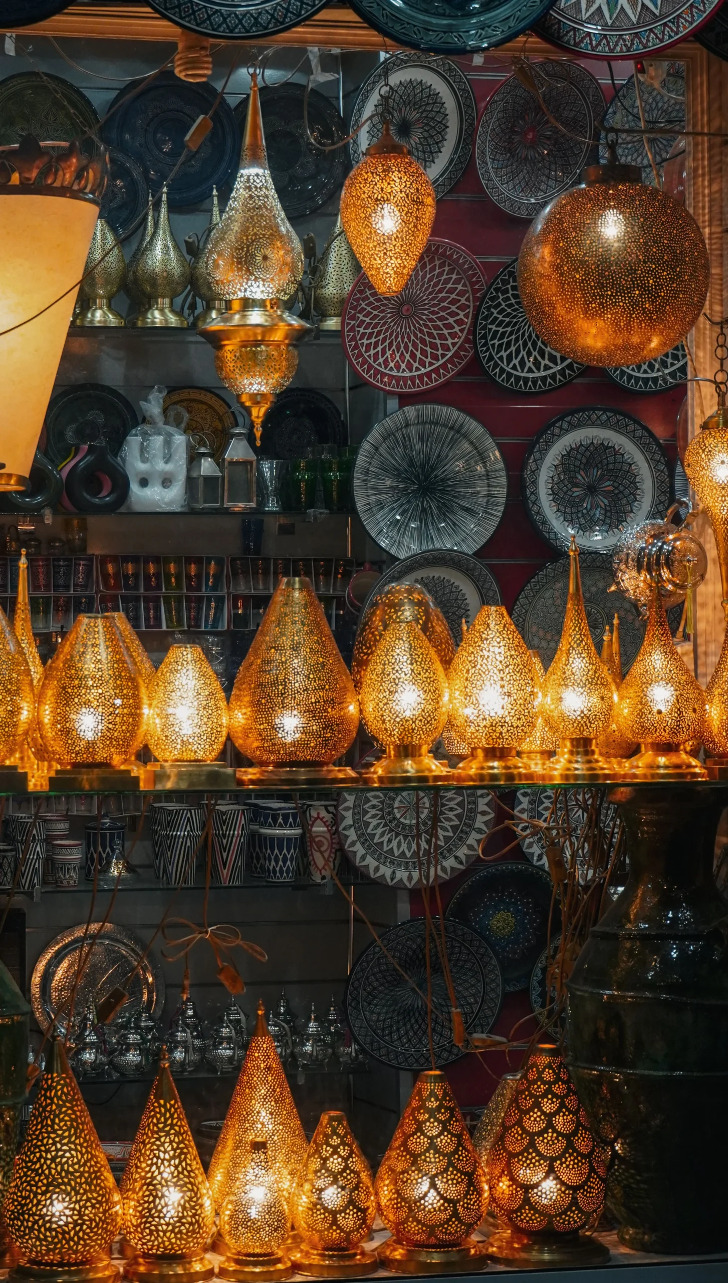 Hand-cut brass lanterns and painted ceramic plates glowing in a lamp shop in the Marrakech souk