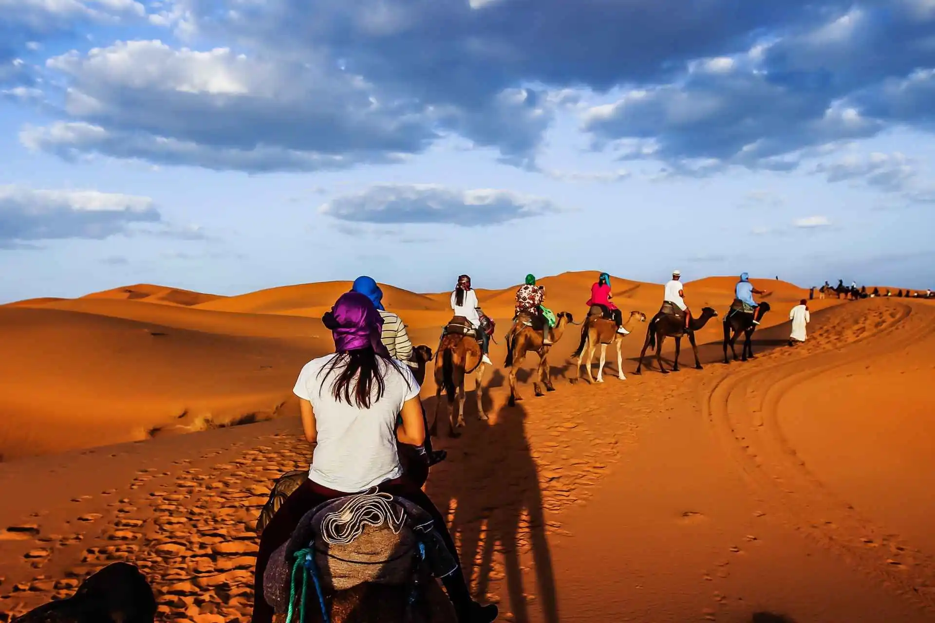 Red carpets and lanterns form a path across the golden desert sand.